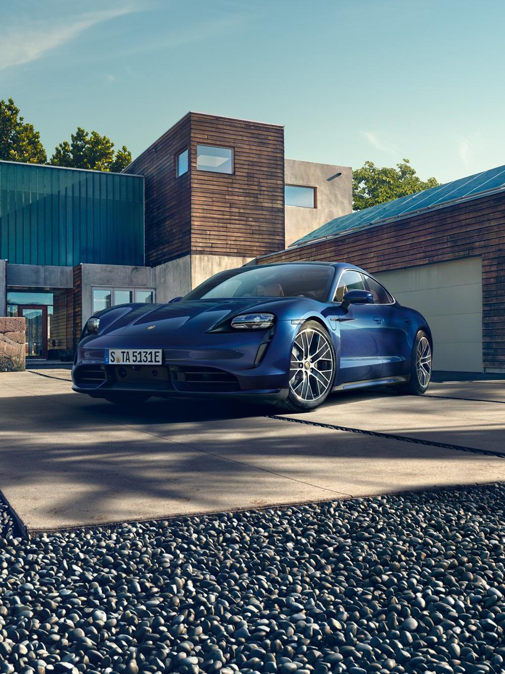 Blue Porsche Taycan outside a modern home